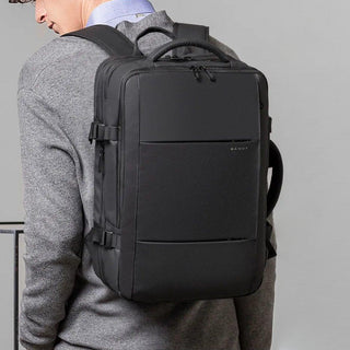 Person wearing a black backpack with a gray background