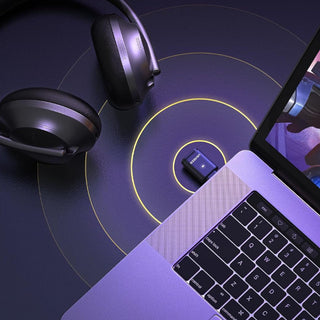 Laptop, headphones, and USB drive on a dark surface with glowing lines.