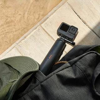 Action camera with a tripod on a jacket and cap on a stone surface