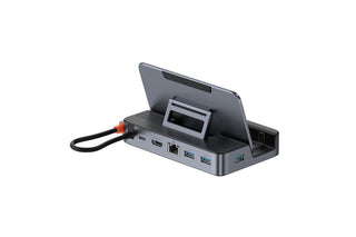 A dark gray multi-port USB hub with an integrated tablet stand, shown with a tablet inserted and a black cable connected on a white background.