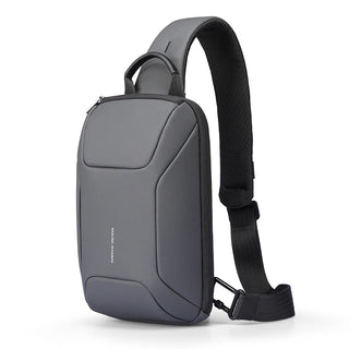 A dark gray and black crossbody sling backpack with a padded shoulder strap, shown from a three-quarter angle on a white background.