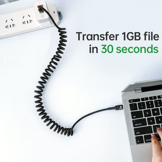 Coiled USB cable connected to a laptop with text 'Transfer 1GB file in 30 seconds' on a white background.