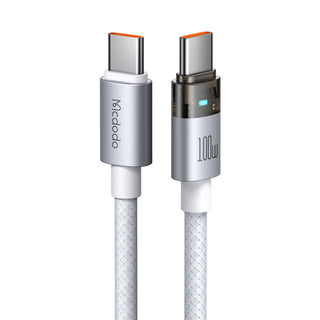A 100M USB-C to USB-C charging cable by Mccdodo, featuring a silver metallic connector housing with an orange accent on the tips, a white braided cable body, and a black 100M marking on the right connector.