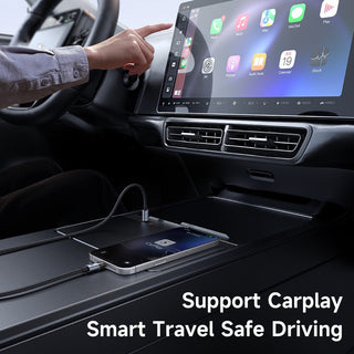 A smartphone sits on a console surface inside a car, connected by a cable to the car's touchscreen infotainment system. A person's hand points toward the screen, and text at the bottom reads 'Support Carplay Smart Travel Safe Driving.