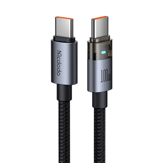 A 100W USB-C to USB-C charging cable by Mcdodo, featuring a black braided body, metallic Black connector housings, and orange accents on the USB-C tips, shown against a plain white background.