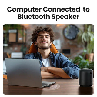 Man using a laptop with a Bluetooth speaker next to him in a home office setting.
